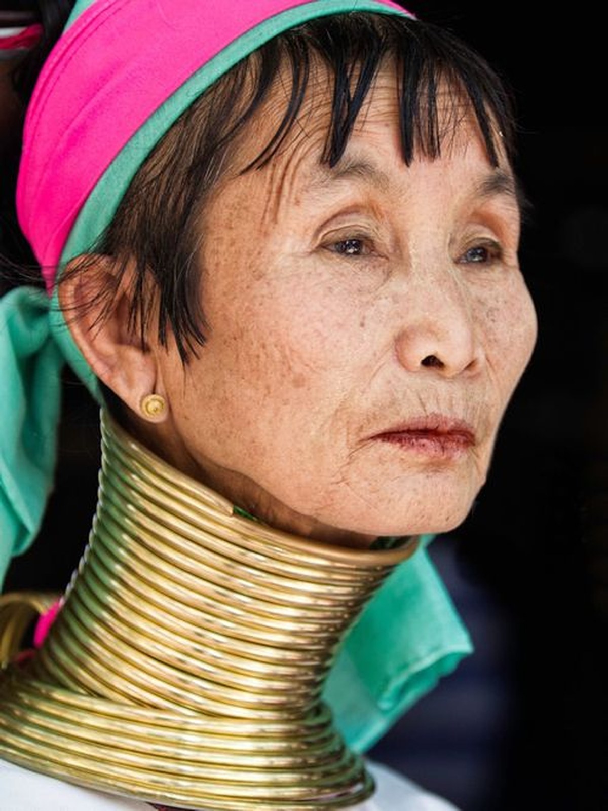 Femme d’une minorité ethnique du nord de la Thaïlande portant des anneaux traditionnels en laiton, rencontre culturelle lors d’un voyage sur mesure en Thaïlande.