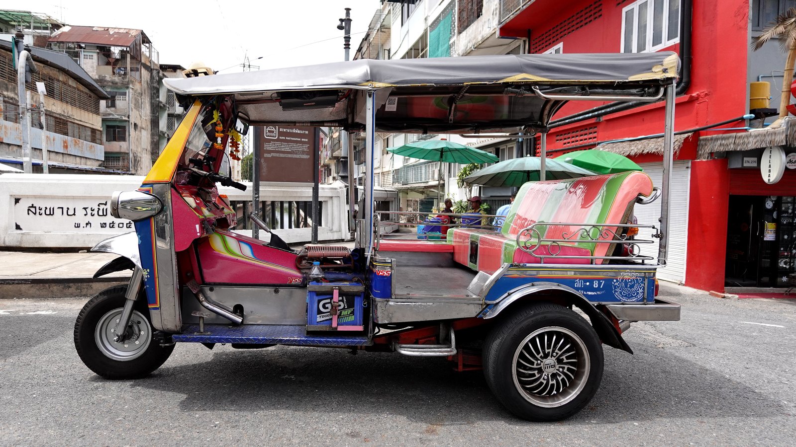 Tuk-tuk circulant dans les quartiers historiques de Bangkok, une manière emblématique d’explorer le patrimoine culturel de la capitale thaïlandaise.