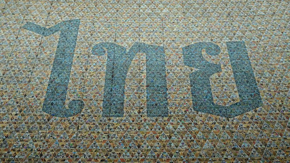 The Thai word « ไทย » (Thai) in large blue letters made from a mosaic of coloured triangles.
