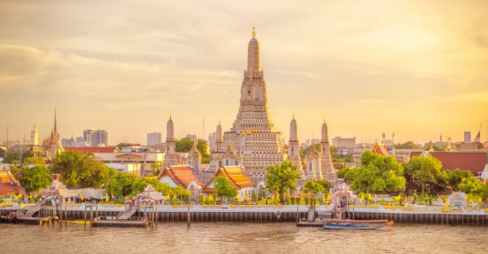 Tall white central prang flanked by four smaller prangs on a riverbank under a golden sky.