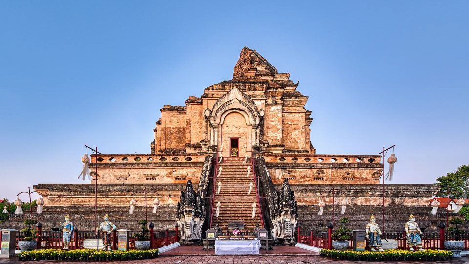 Large partly ruined brick chedi with a central staircase flanked by nagas and guardian statues at its base.